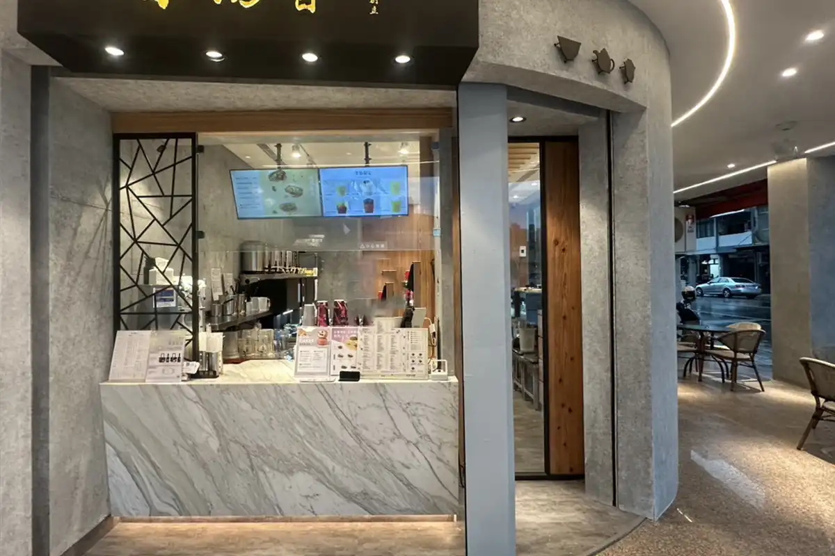 飲料店店面,牆面與騎樓圓柱為清水模質感飾面,櫃檯為白色大理石