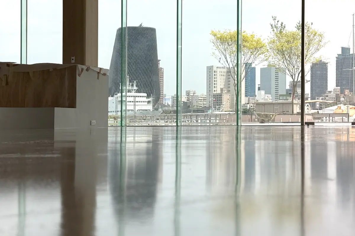 餐廳深灰色高光澤地坪,映出落地玻璃窗與窗外的港邊建築