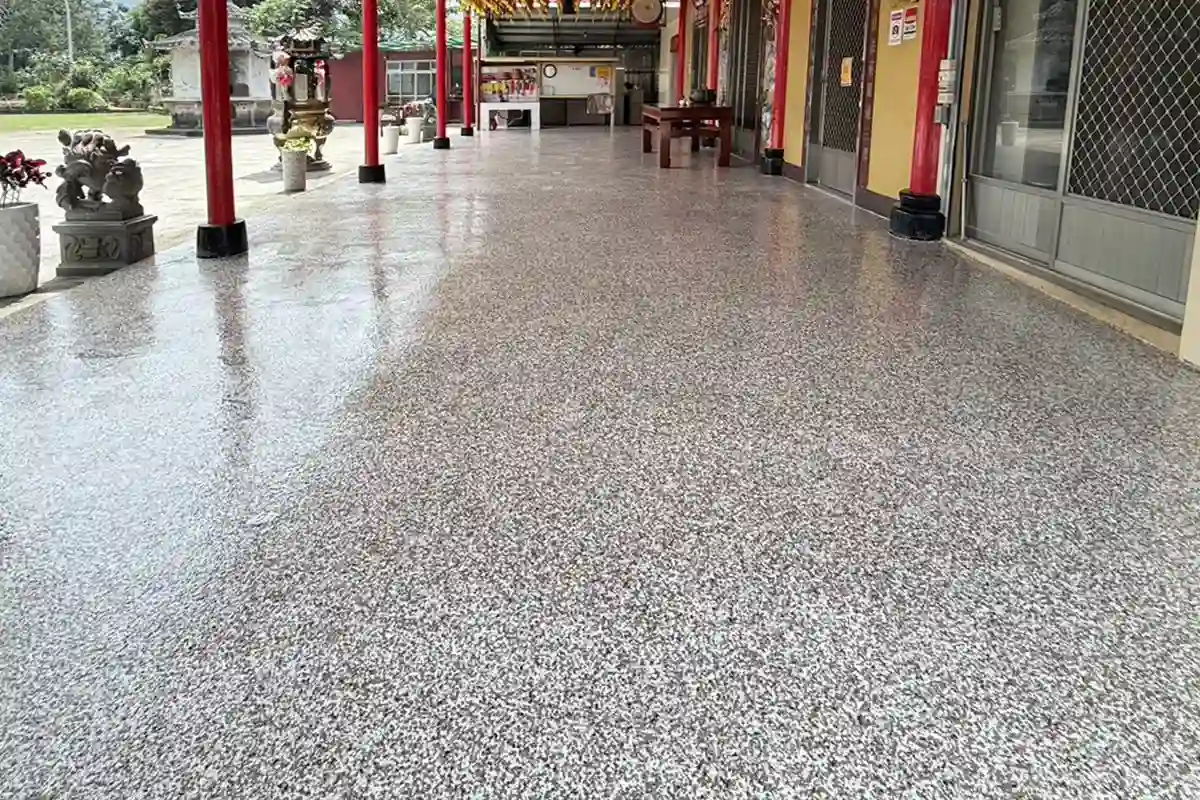 廟宇廊道的灰白色片岩地坪,左側為紅色廊柱與石獅,右側為門窗