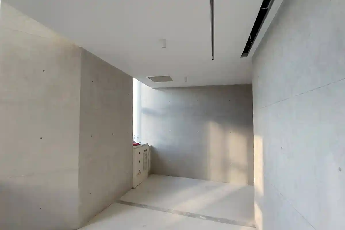淺色清水模室內牆面,有分割線與規則排列的螺栓孔